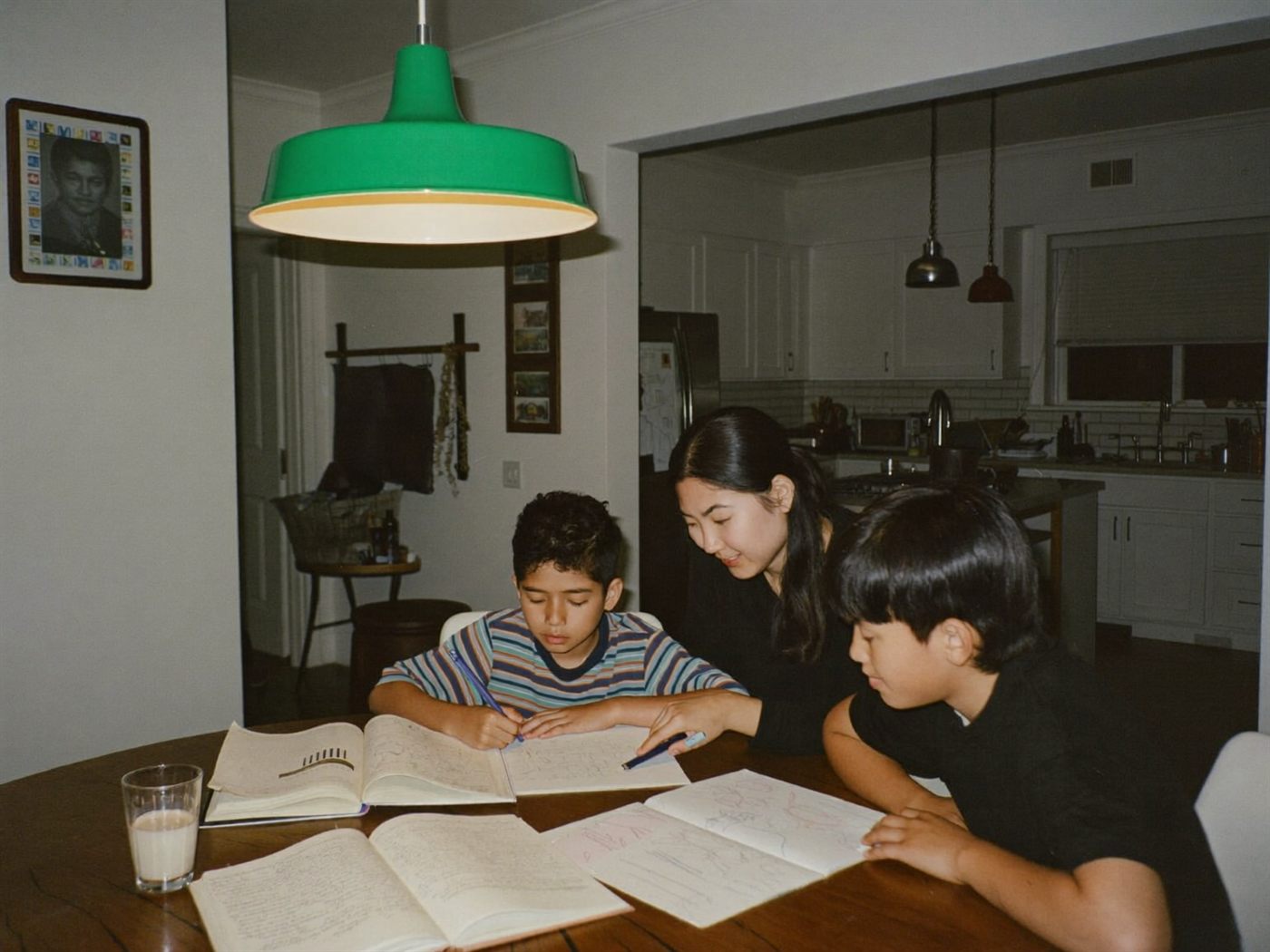 A mother helping her sons with homework at the kitchen table
