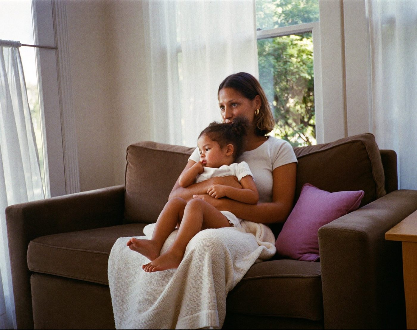 A mother holding her young daughter close on the sofa
